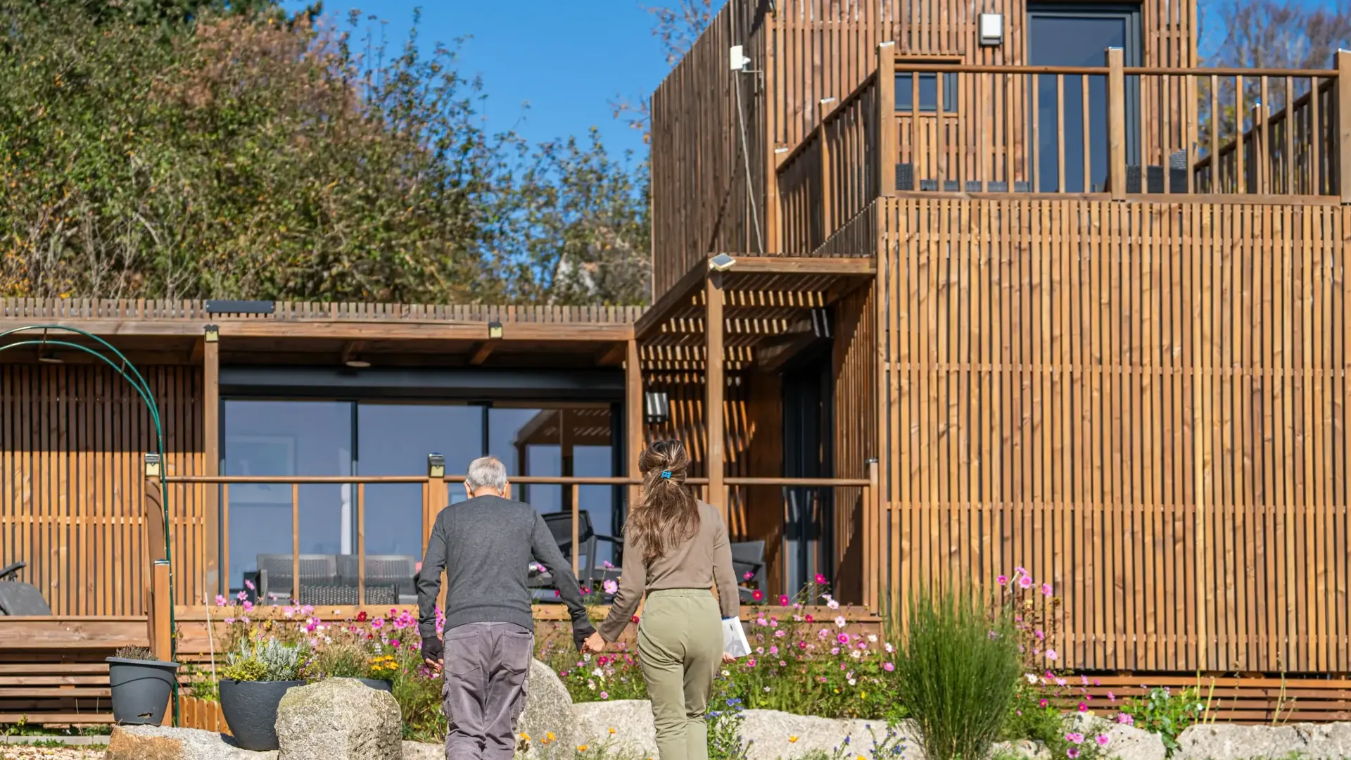 Un couple rejoint son studio de jardin Greenkub GK50T en ossature bois, à quelques pas de la maison