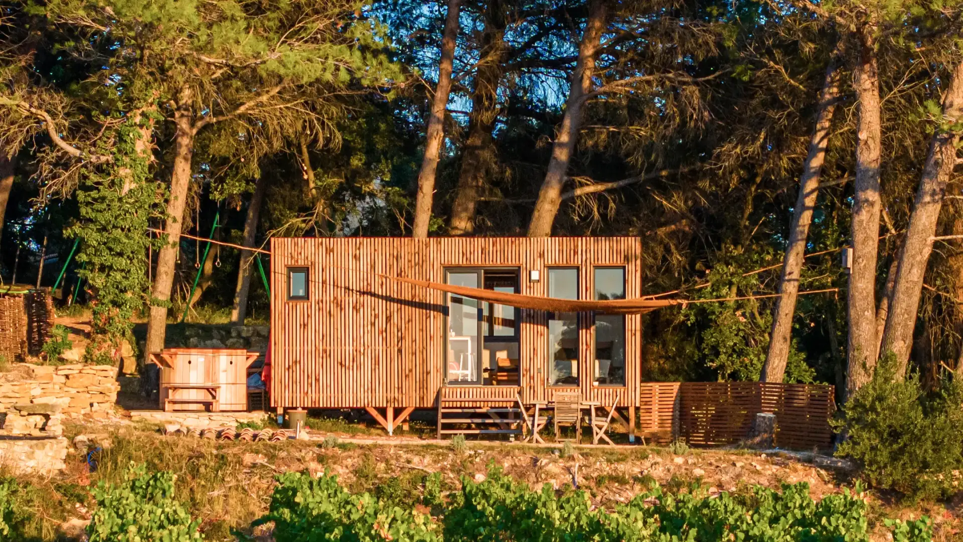 Studio bois compact Greenkub en ossature bois, posé sur pilotis au couchant en lisière de vignes : l'alternative fixe à la tiny house