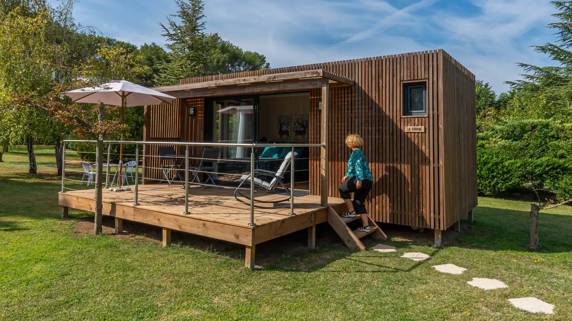 Studio de jardin Greenkub GK20 de 20 m² en ossature bois et sa terrasse, dans un jardin familial