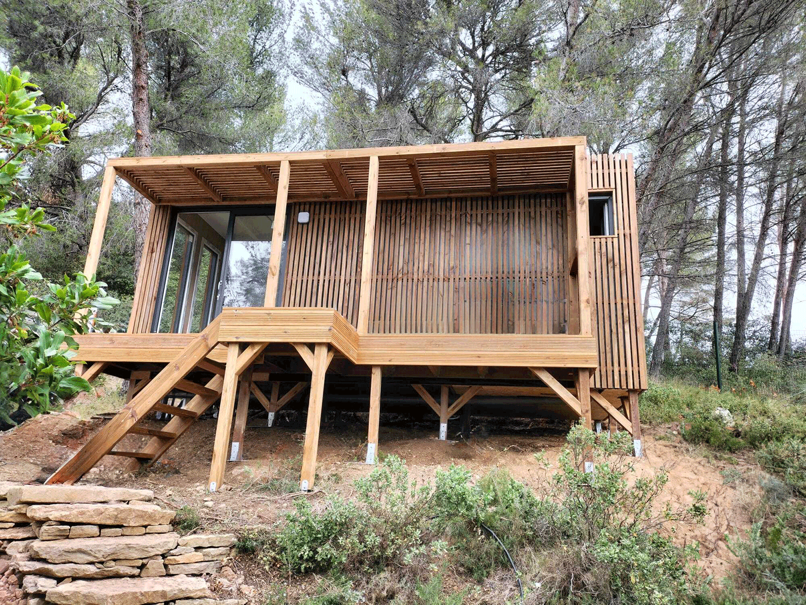 Studio en bois sur pilotis dans un bois