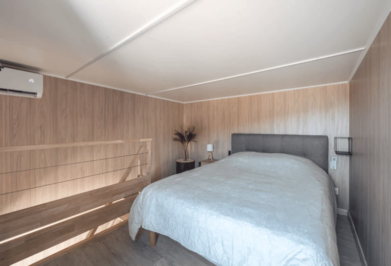 Une chambre sur la mezzanine d'une construction bois