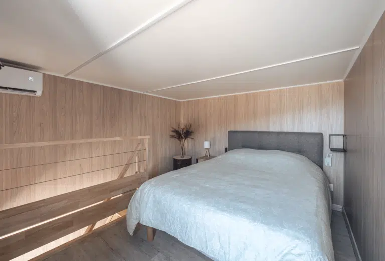 Une chambre sur la mezzanine d'une construction bois