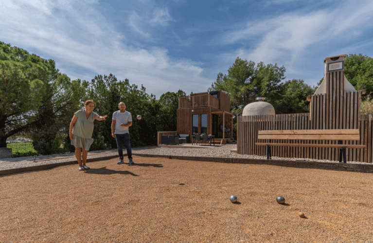 Des personnes jouant à la pétanque devant une maison en bois
