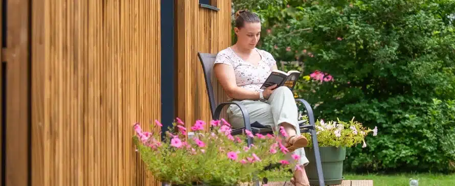 Femme souriante à l'entrée de son bureau de jardin en bois Greenkub