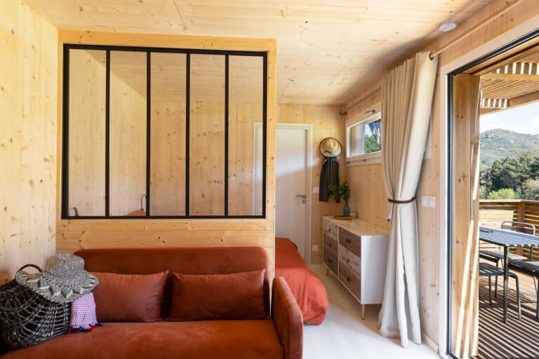 Intérieur d'un Greenkub GK20 : coin cuisine équipé avec évier, micro-ondes et plaques, ouvert sur la chambre