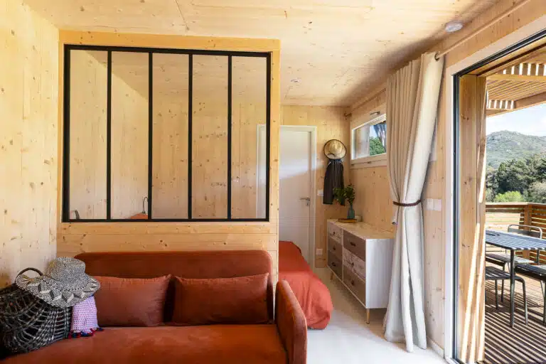 Intérieur d'un Greenkub GK20 : coin cuisine équipé avec évier, micro-ondes et plaques, ouvert sur la chambre