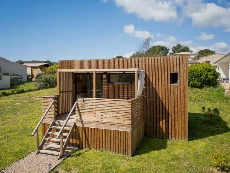 Greenkub GK20 en location saisonnière : extérieur bois chaleureux, terrasse ombragée et accès paysagé