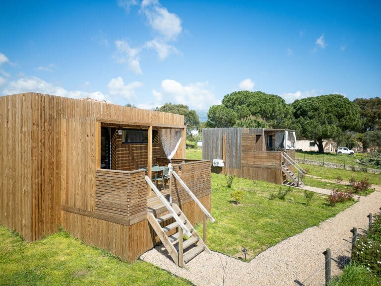 Studio bois GK20 Greenkub avec terrasse couverte et balustrade en lames de bois, cadre naturel et verdure