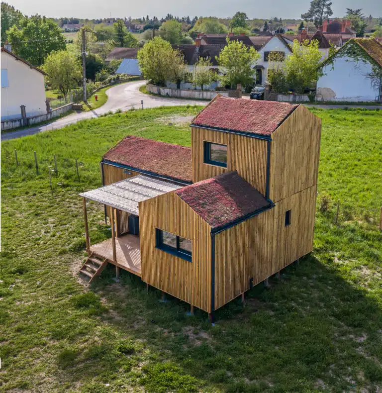 Vue aérienne d'une maison modulaire bois Greenkub GK50 en Allier – composition de trois volumes bardage bois vertical avec toitures végétalisées, terrasse centrale couverte, environnement rural