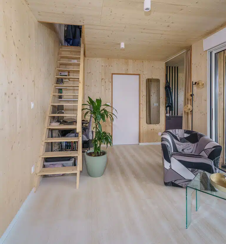 Intérieur maison modulaire 50m² avec mezzanine – murs bois massif, escalier en bois clair, lumière naturelle