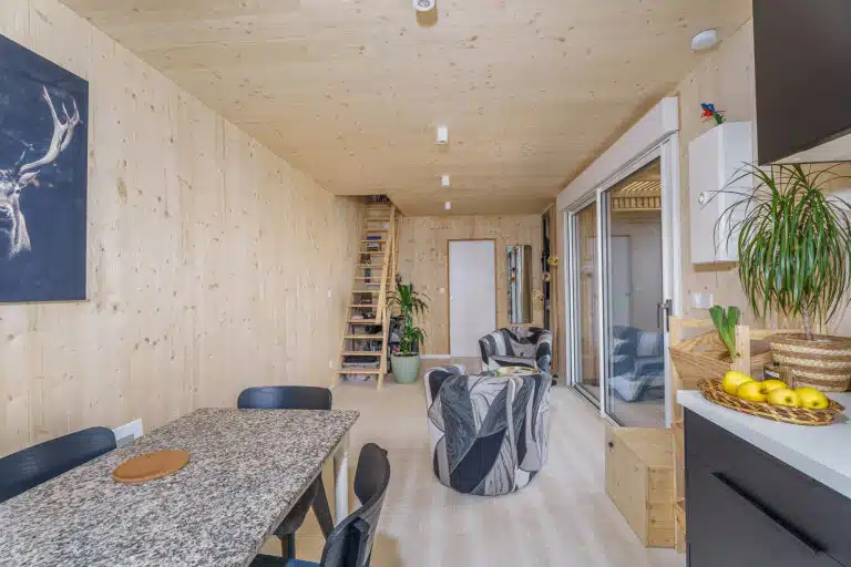Intérieur maison modulaire 50m² avec mezzanine – murs bois massif, escalier en bois clair, lumière naturelle